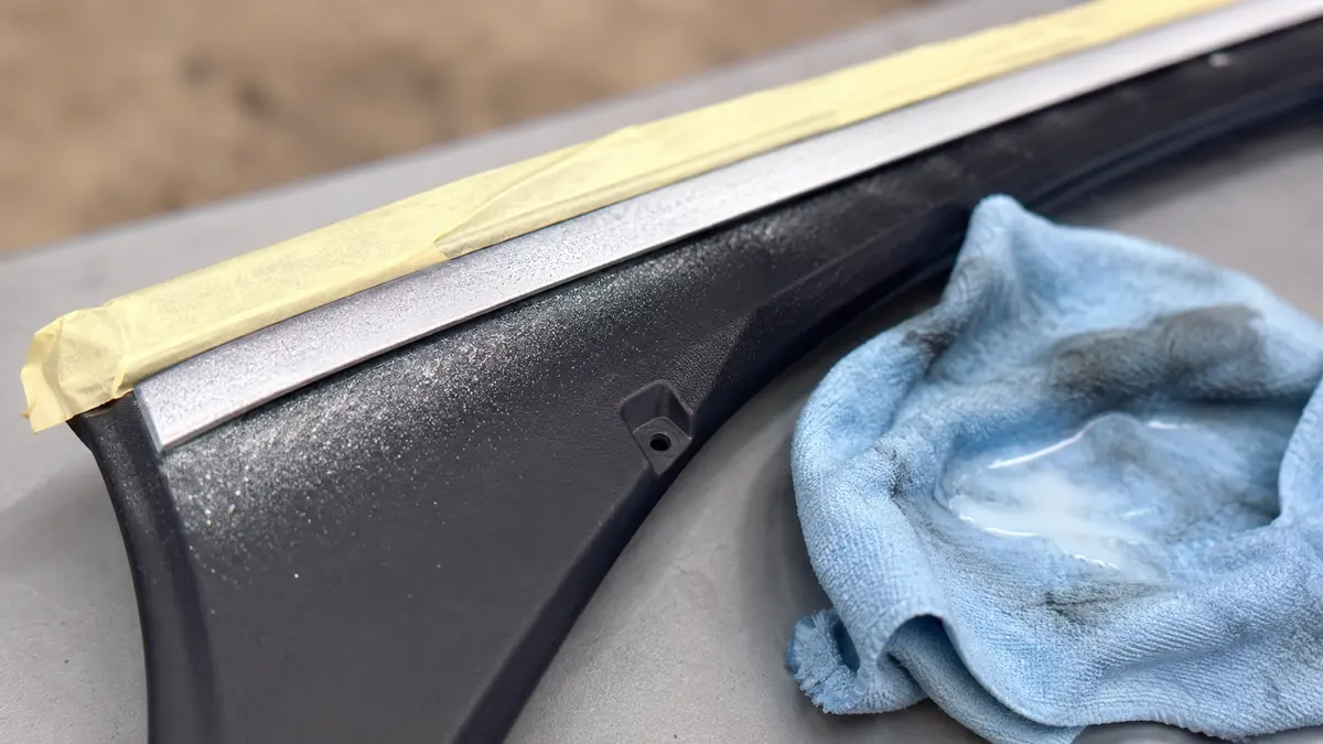 Overspray von Chromlack auf Kunststoffflaeche neben abgeklebter Zierleiste, Reinigung mit Lackreiniger